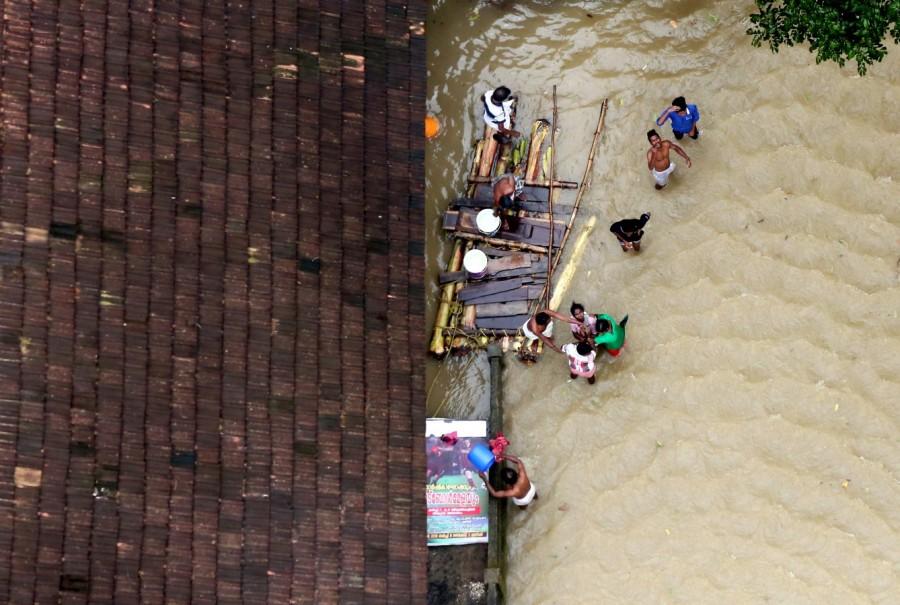 People wait for aid next to makeshift raft at a flooded area Kerala floods,Kerala floods pics,Kerala floods images,Kerala floods stills,Kerala floods pictures,Kerala floods photos,Kerala worst flood
