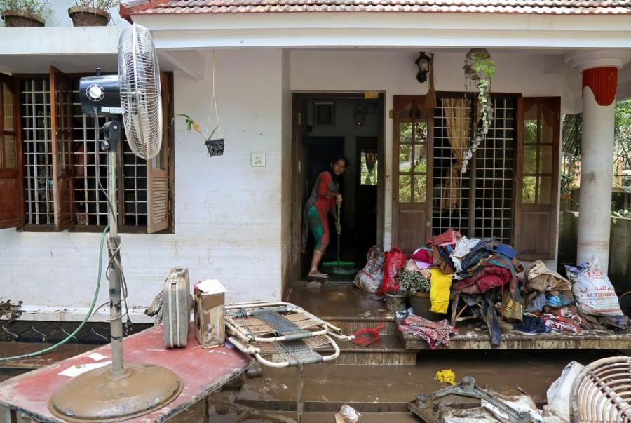 A woman cleans the mud from the entrance of her house Kerala floods,Kerala floods pics,Kerala floods images,Kerala floods stills,Kerala floods pictures,Kerala floods photos,Kerala worst flood