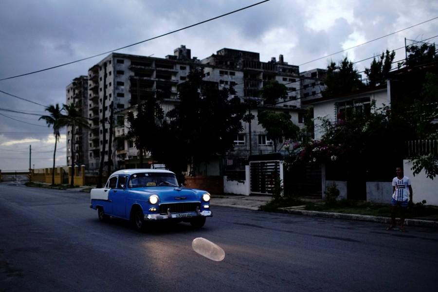 A vintage car passes by an inflated condom From fishing to tying hair,Condom Uses,Condom Use,Condom Use Goes Far Beyond Sex,condom usage,Cuba goes far beyond sex